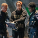 Daniel Craig, director Cary Joji Fukunaga, and Lashana Lynch staring at a screen while filming No Time to Die.